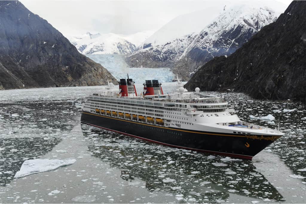 Luxury cruise ship sailing through icy fjord surrounded by snow-capped mountains, adventure travel with 407 and Beyond Vacation Co.