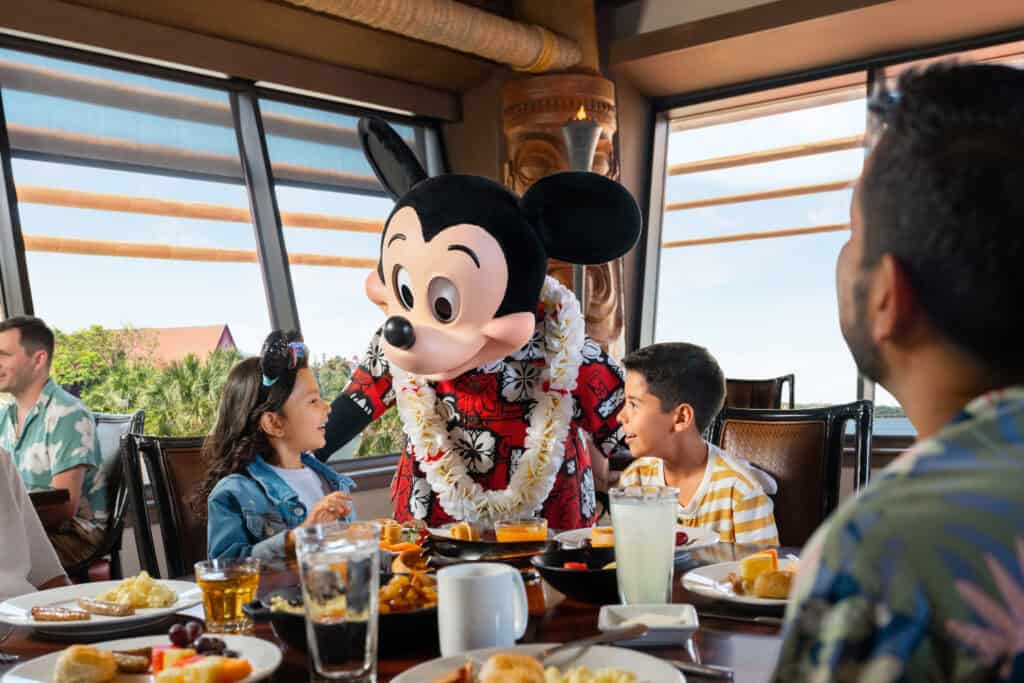 Mickey Mouse greeting guests at Disney World restaurant during dining experience.
