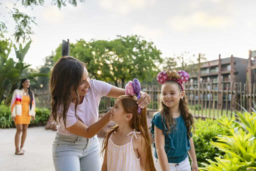 Family enjoying outdoor fun with children wearing Minnie Mouse ears and smiling.