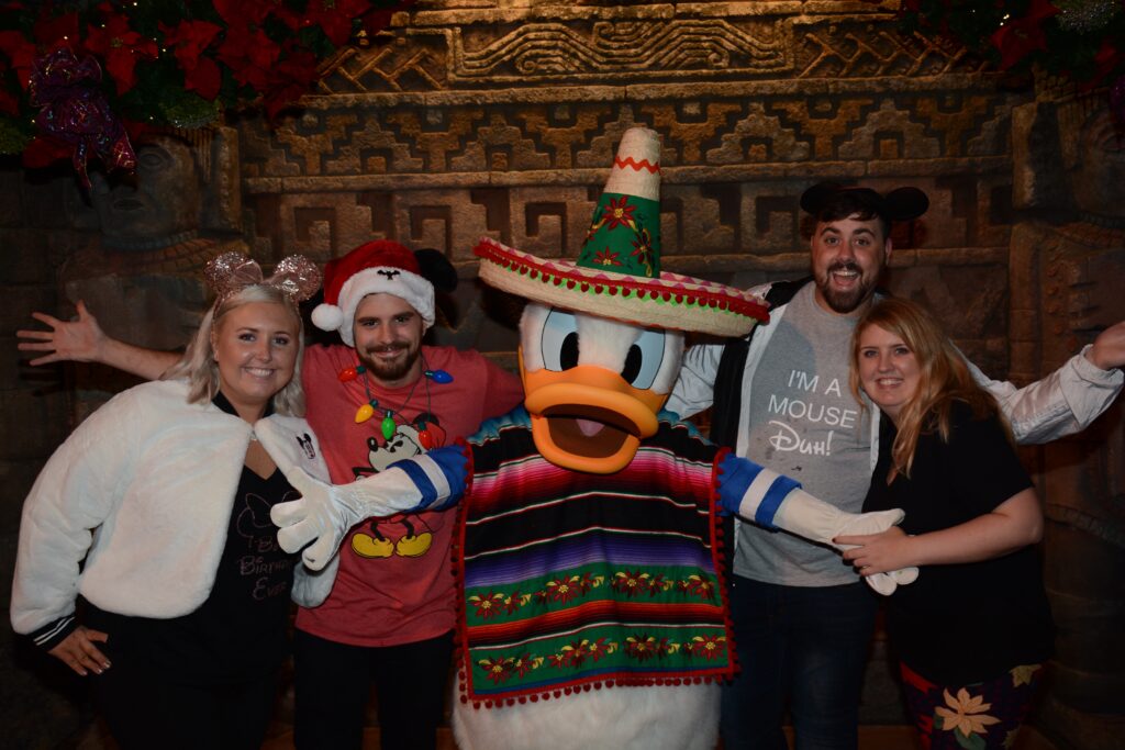 Group of people with Disney characters in Christmas costumes at Disney park.