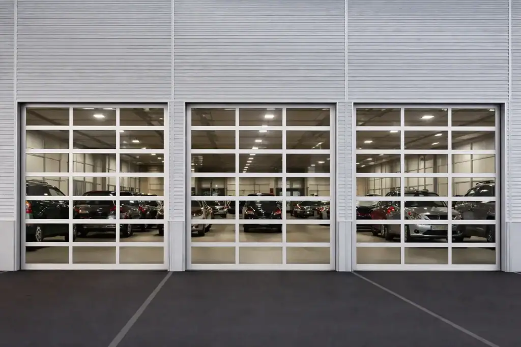 Three-bay full-view aluminum sectional doors installed at a luxury car showroom, utilizing large-span tempered glass to create a 24/7 visual marketing display.