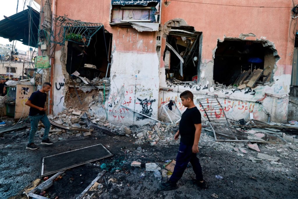 Boys walk past a damaged building at the Nur Shams refugee camp in the northern occupied West Bank city of Tulkarm. Photo by JAAFAR ASHTIYEH/AFP via Getty Images.
