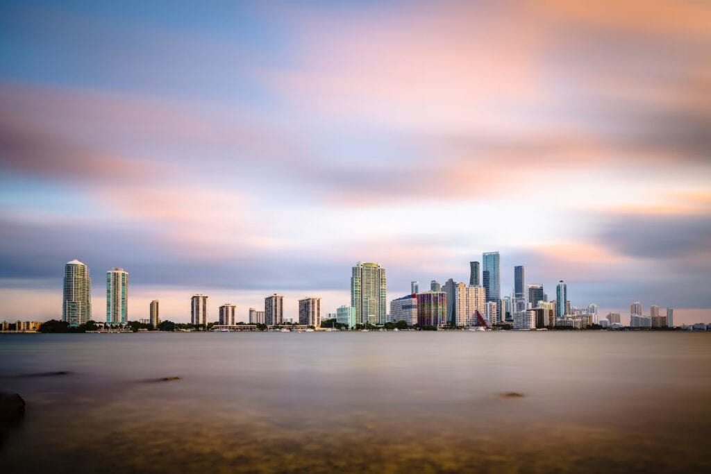 Panorámica del downtown de Miami, Florida, con rascacielos modernos e iluminación urbana reflejada sobre la bahía.