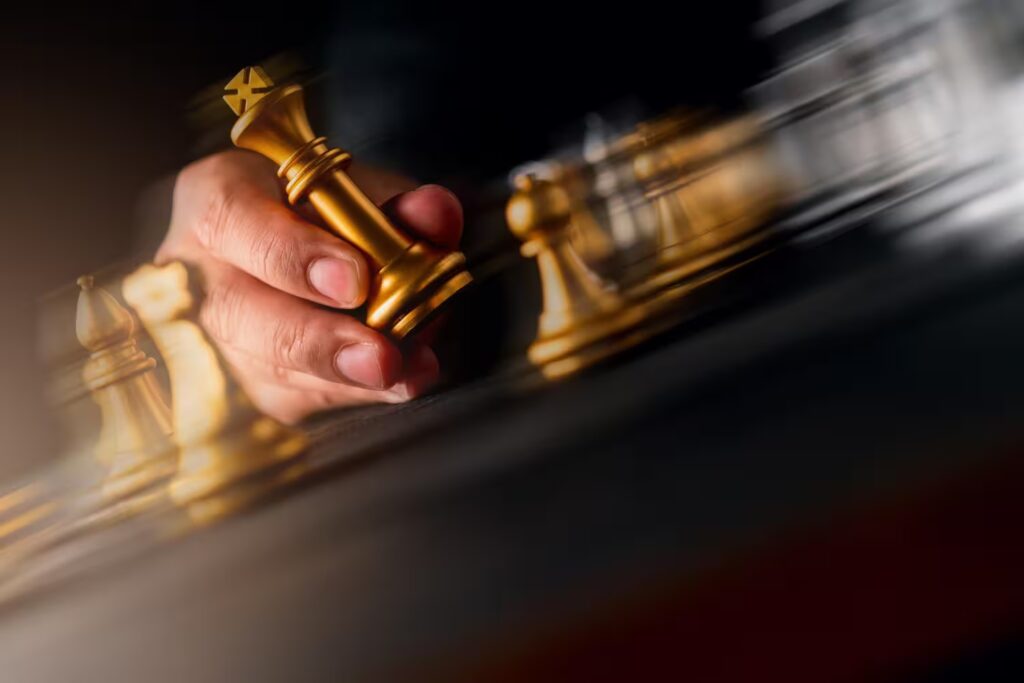 Hand moving a golden chess piece on a board—symbol of strategy, leadership, and disciplined corporate planning. Real Estate Investing How To
