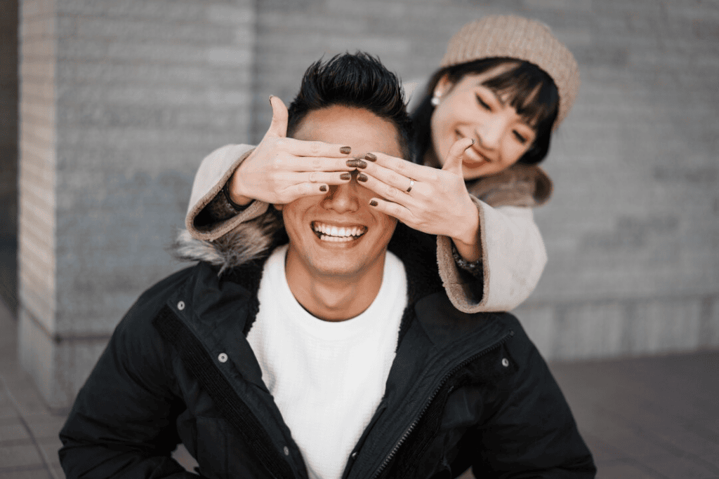 Femme cachant les yeux de son petit ami - le couple souri