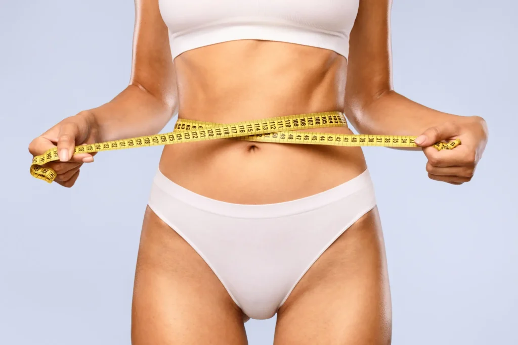 Woman holding tape measure around wait after body treatment