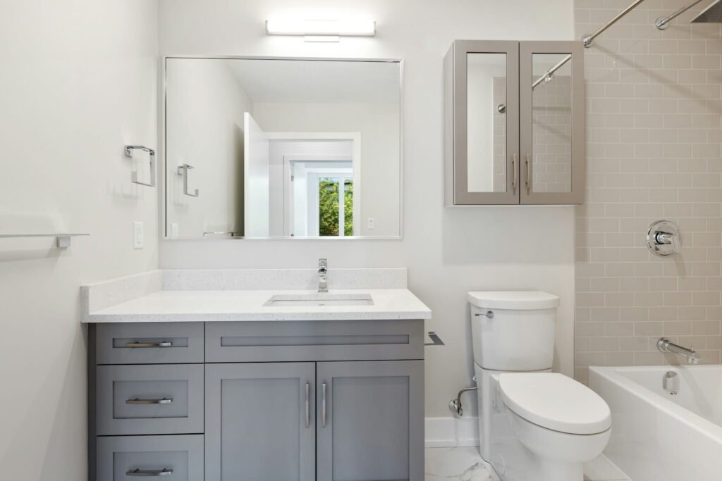 Grey vanity bathroom with tub and shower, typical budget-tier 5x10 bathroom remodel