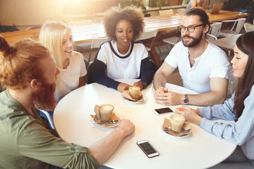 A group of friends sitting around a table in a coffee shop, enjoying coffee and conversation.