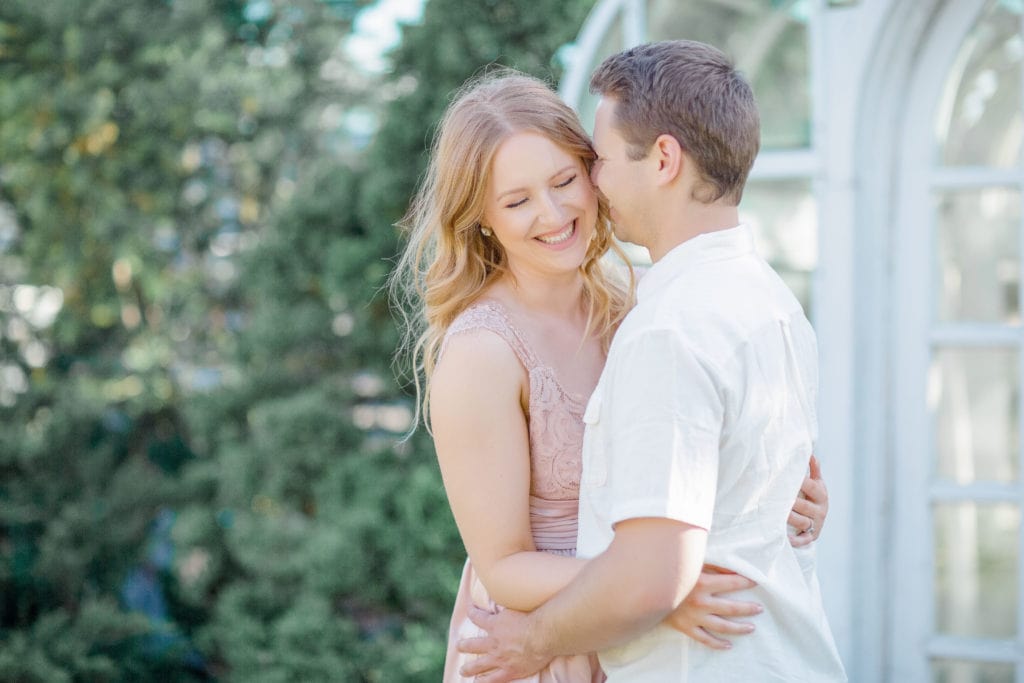 Couple laughing in front of the Tropical Gardens wearing a pink dress and white linen shirt Couple in a white sweater and jean outfit hugging and laughing in front of an willow Tree in the Dominion Arboretum during an engagement session engaged couple walking through magnolia blossoming trees, dominion arboretum Ottawa, white magnolias, engagement photo with a dog spring cherry blossom Engagement Session Downtown Ottawa during Sunset grey loft studio ottawa wedding photographer videographer engagement kanata orleans nepean beautiful locations for engagement photos in ottawa dominion arboretum magnolia blooms spring photos ottawa photo studio boxer puppy ottawa dogs in engagement photos ottawa