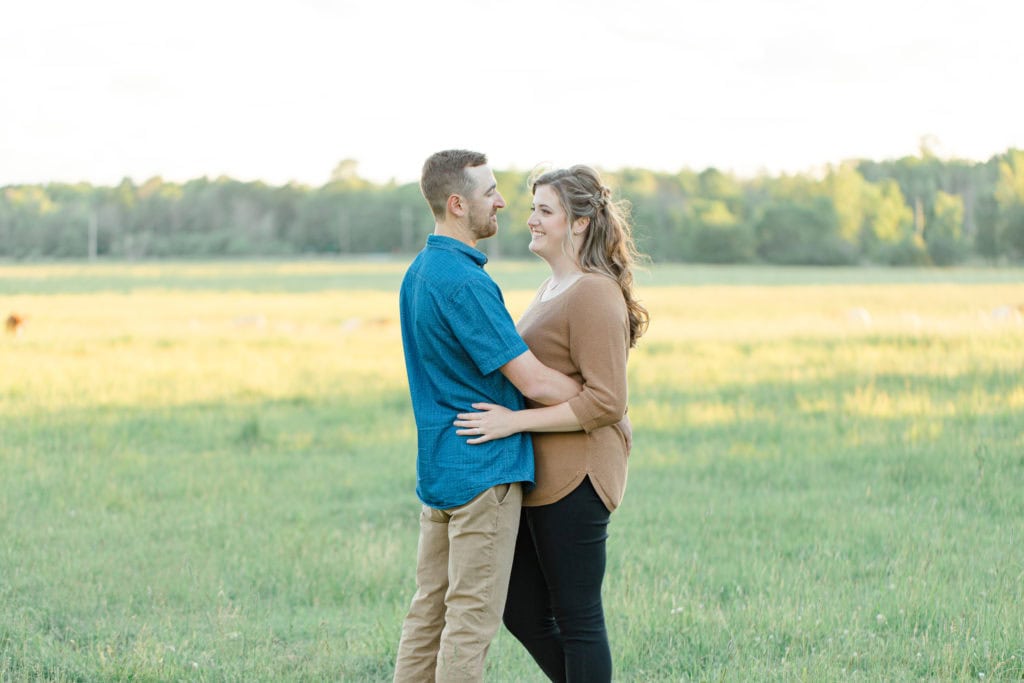 Cows during Engagement Session - Poses during Engagement Session Sunset - Natural Posing for Photo Session - Couples Photo Session Fun - Fun on the Farm - Farm Engagement Session - Blue and Brown Engagement Session Inspiration - Natural Engagement Session Posing - Ideas for what to wear for Engagement Photography, Modern Engagement Session Inspiration Wardrobe Ideas. Unsure of what to wear for your engagement photos, we've got you! Romantic brown with black leggings for Summer Engagement in Almonte. Grey Loft Studio is Ottawa's Wedding and Engagement Photographer for Real couples, showcasing photos that are modern, bright, and fun.