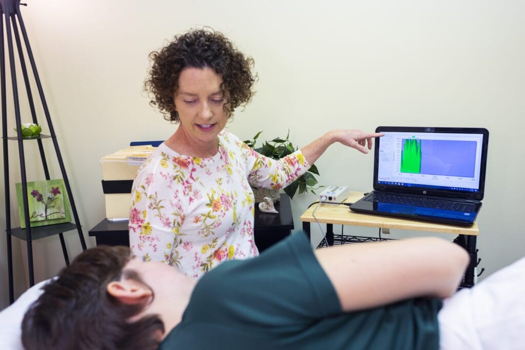 Therapist showing patient data on laptop.