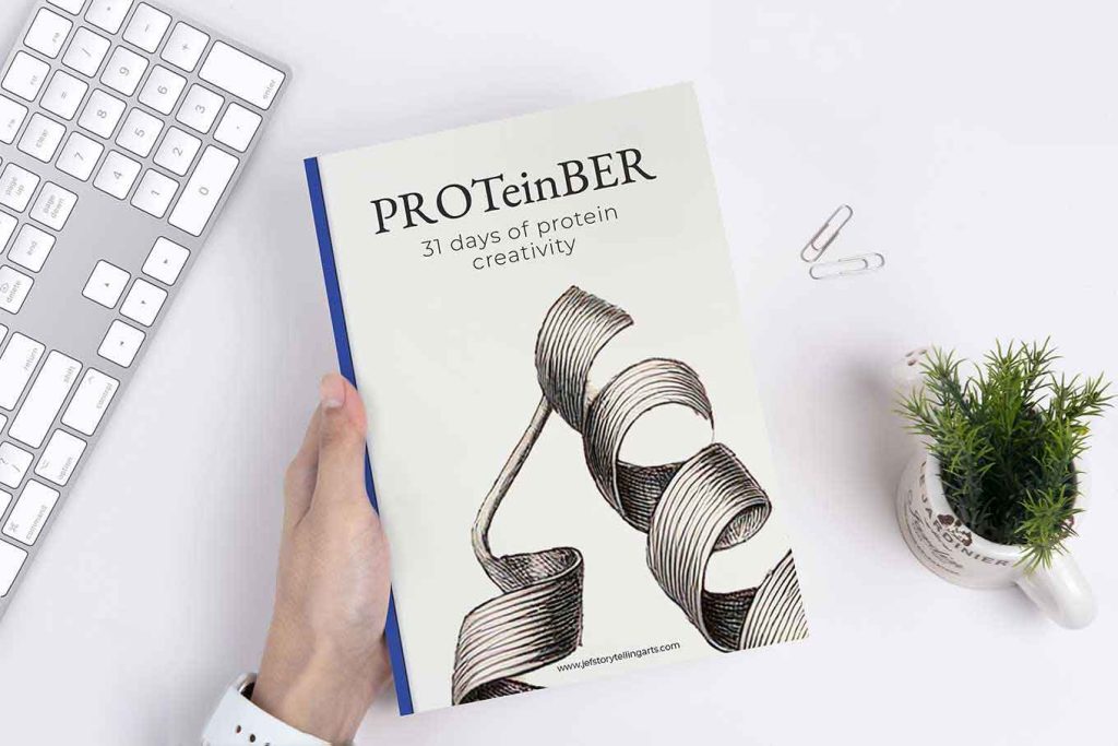 A person holding JEFS Proteinber book over a desk top scene