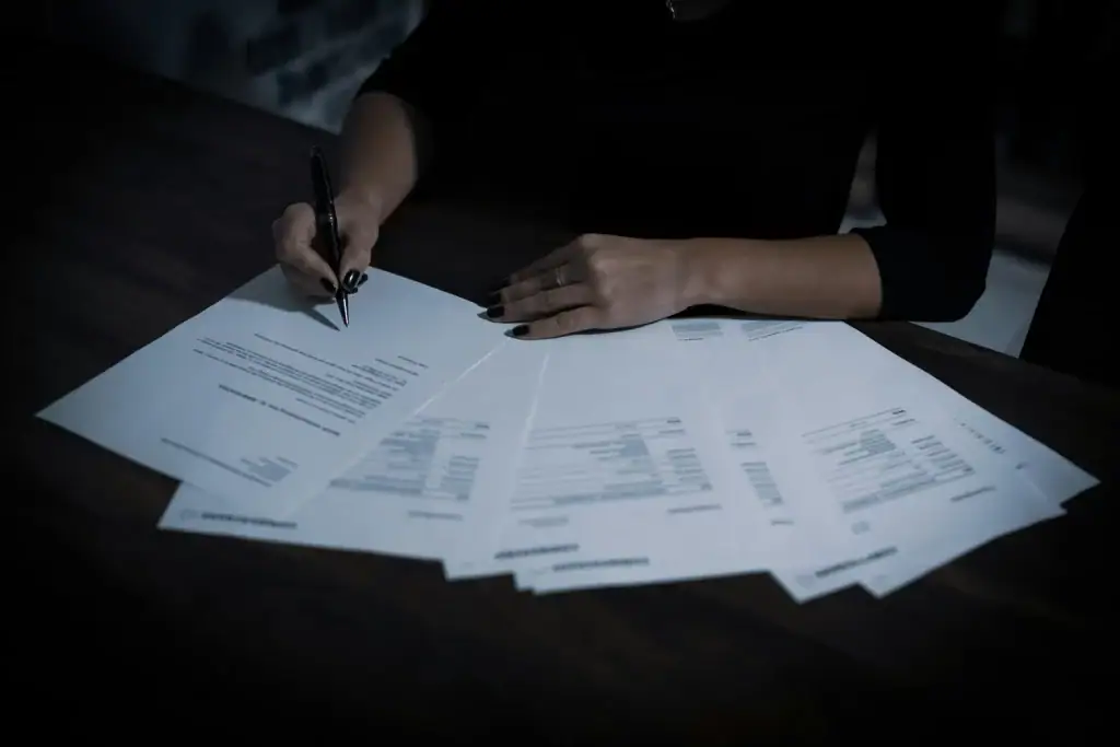 Hands reviewing multiple pages of a commercial contract on a dark desk — penalty clause under Article 551 of the Ukrainian Civil Code