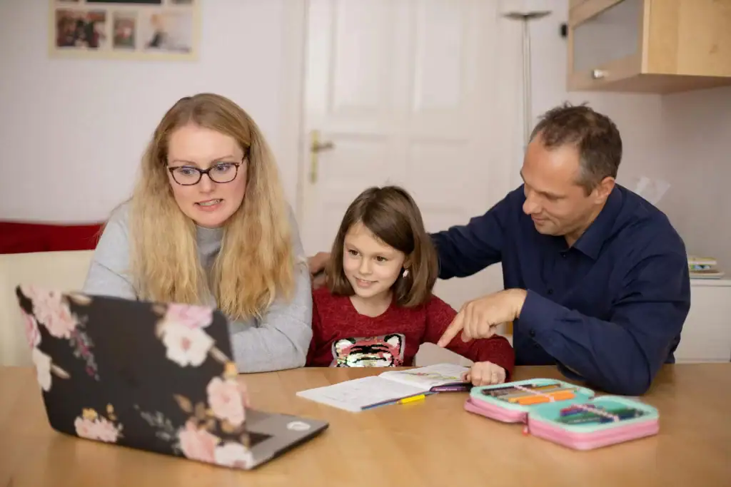 A family sitting in front of a laptop, depicting a tutoring session with an online tutor for tutoring.