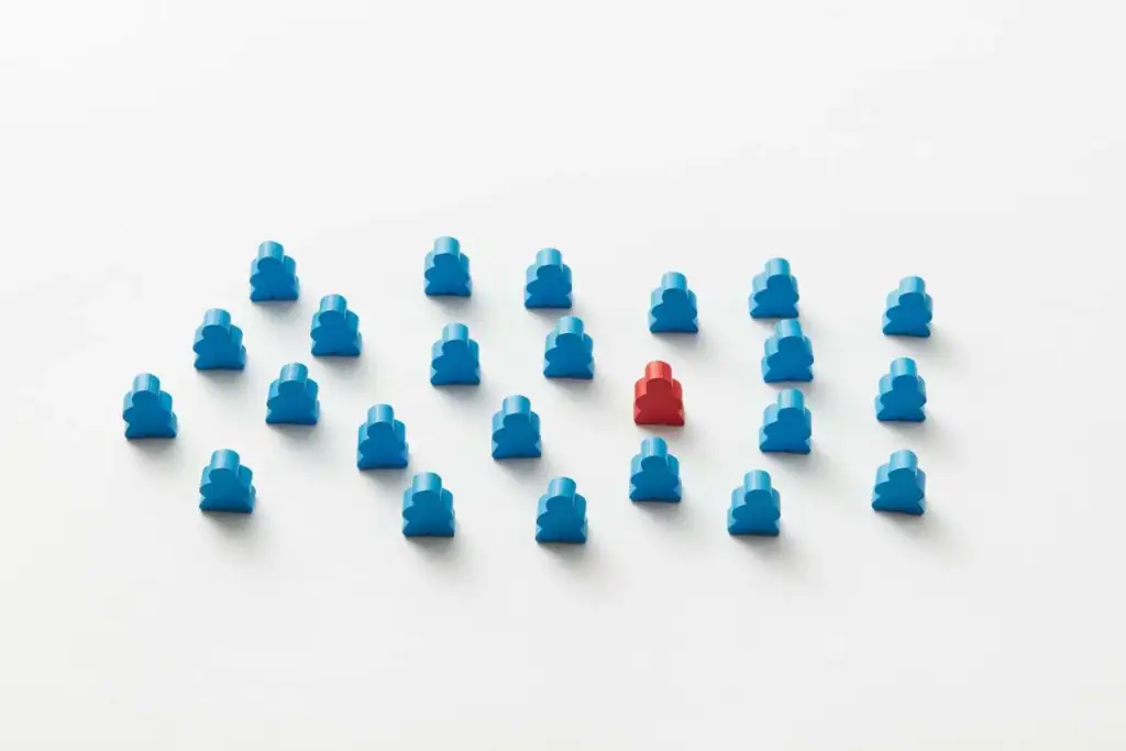 A red meeple standing out among a group of blue meeples, symbolising standing out from other job candidates
