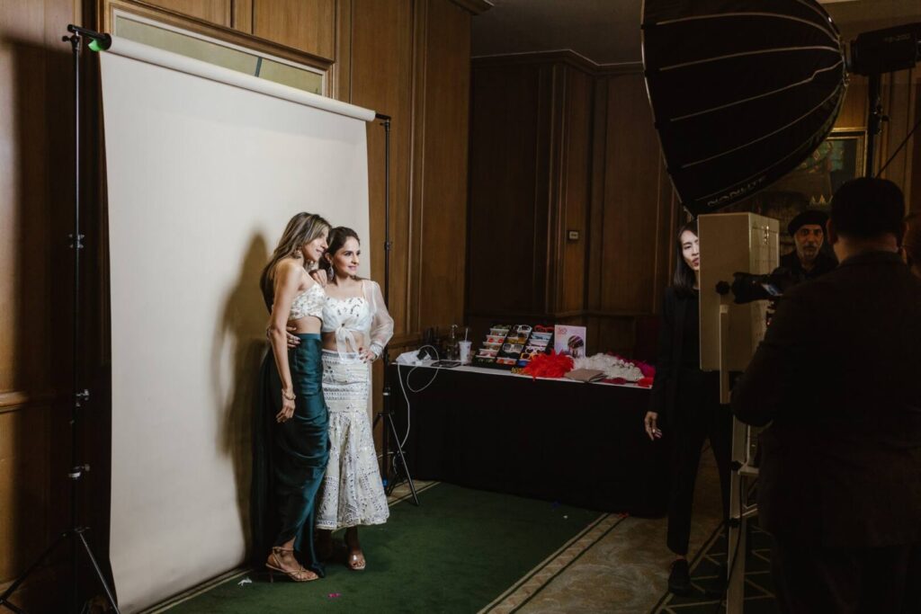 Two guests posing at the white backdrop of the Koro Films studio photo booth as the attendant checks the shot