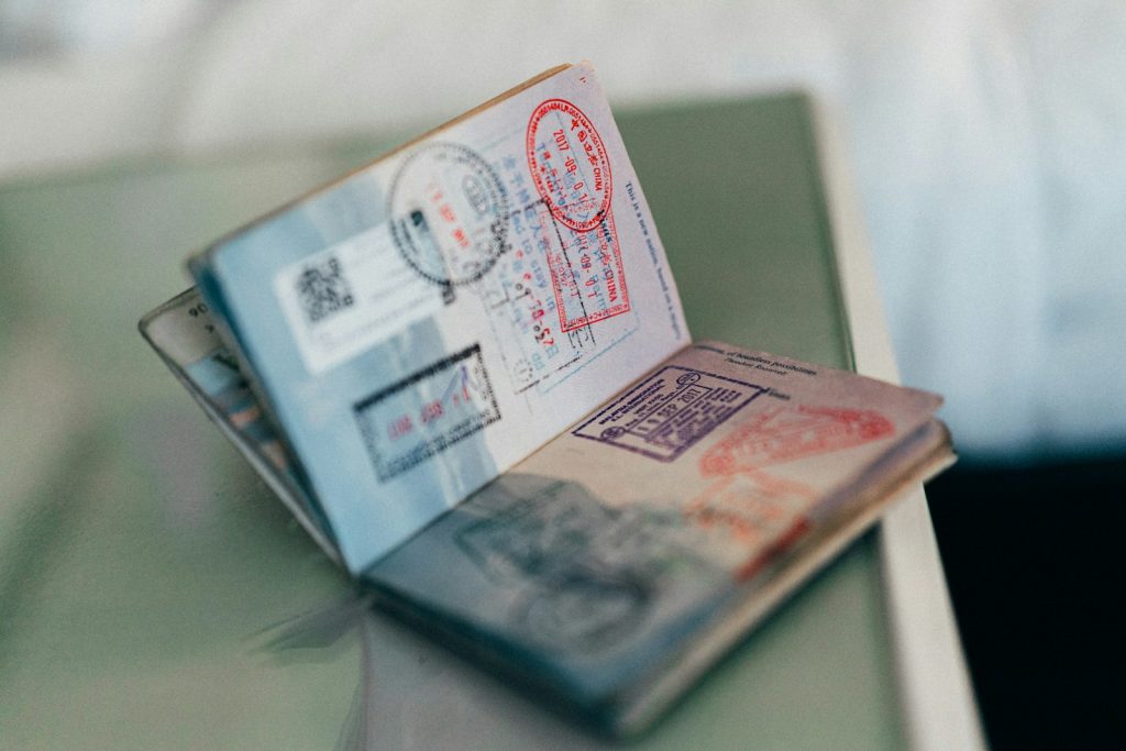 An open passport showing multiple Schengen visa and border ink stamps, illustrating international travel and health insurance requirements