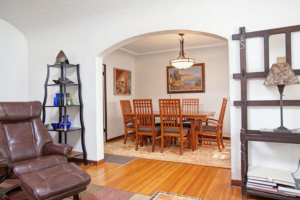 Interior view of 3317-3319 Boundary Street in North Park showing the transition from the living area with hardwood floors to a formal dining room through a classic arched doorway.