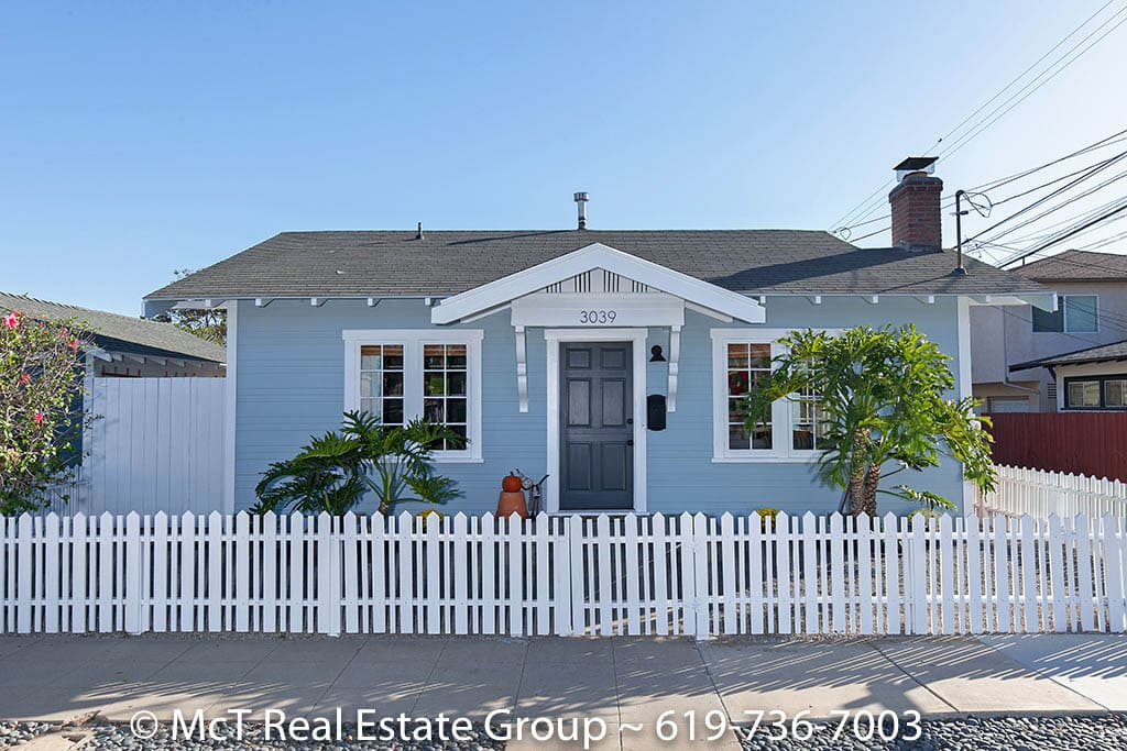 Renovated kitchen at 3039 Dwight Street in North Park featuring custom grey cabinetry, a classic subway tile backsplash, and high-end stainless steel appliances including a professional-grade gas range.
