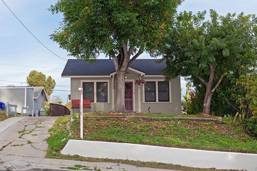 South Park home at 1739 31st Street features light sage siding, a gabled entryway with a red front door, and a shaded front yard with a mature tree.