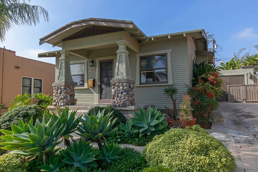 Green Craftsman house in North park with low maintenance garden in the front- long driveway leads to a garage