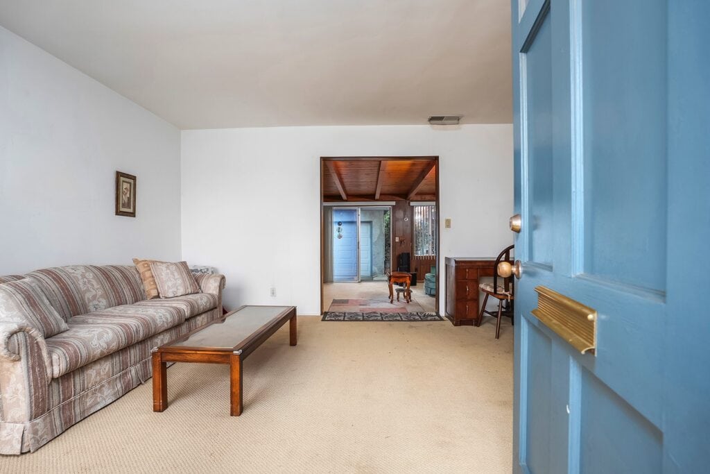 Living room interior of a mid-century home at 1751 39th Street in San Diego, featuring original 1950s architecture, wood-beamed ceilings, and a view into the sunroom near North Park