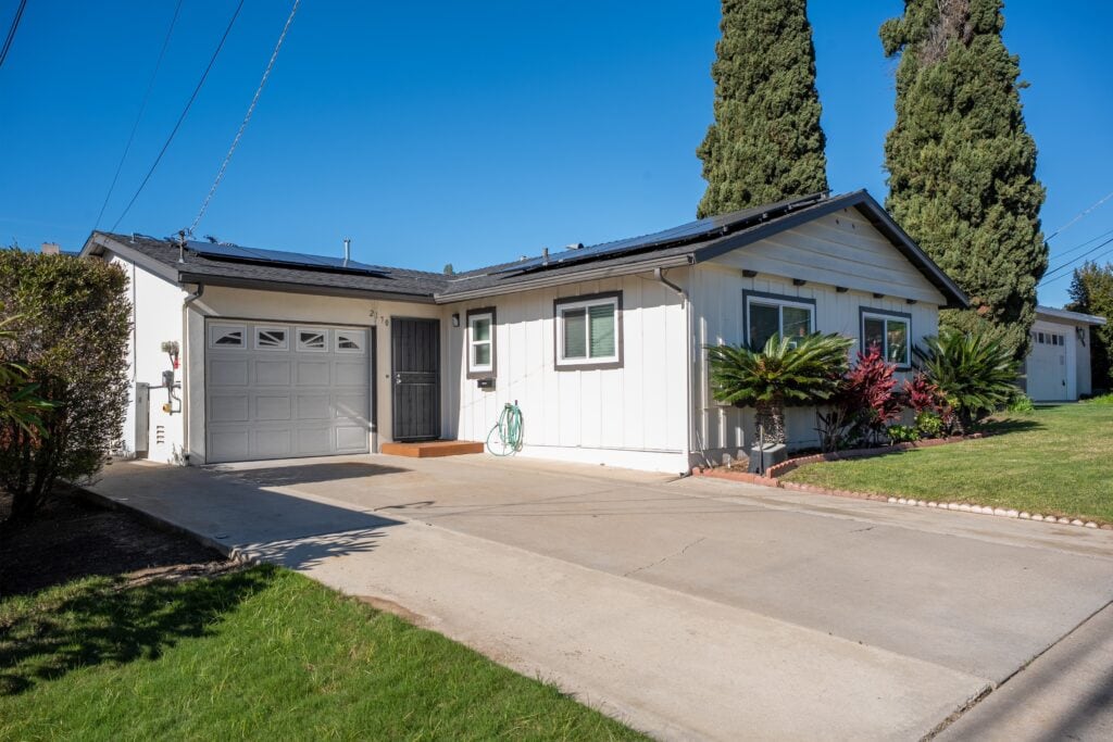 Close-up exterior view of the front of 2170 Montclair St in North Park, highlighting the sago palms and red tropical plants.