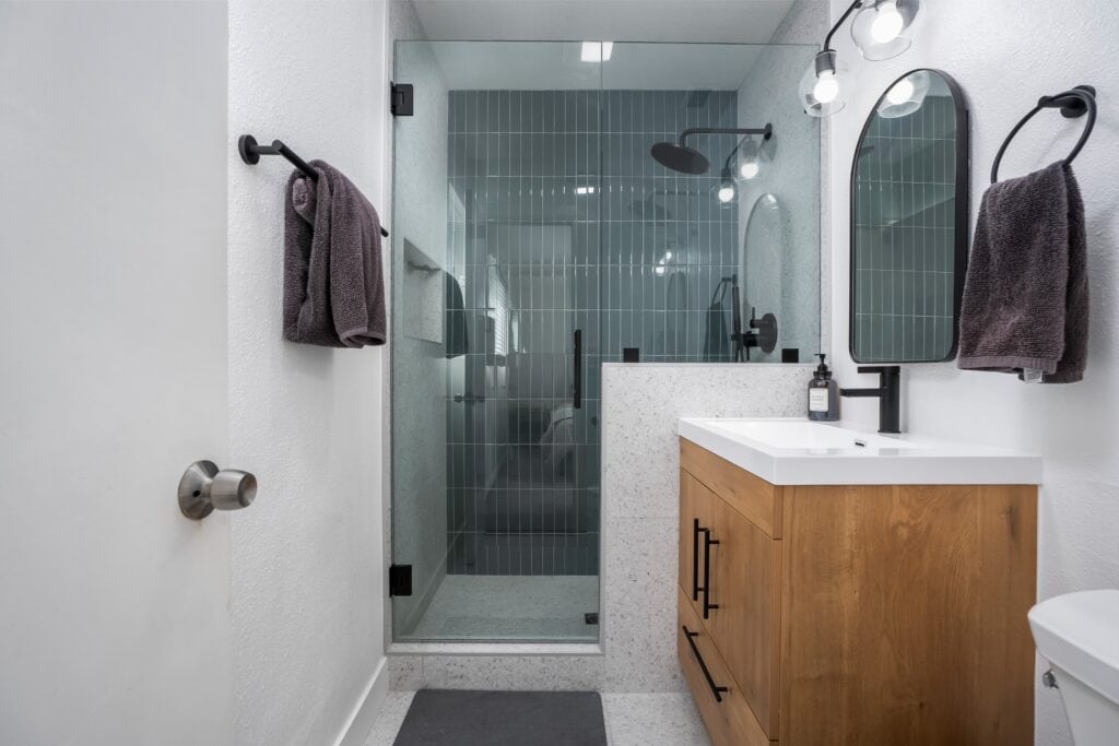 Newly remodeled bathroom at 2170 Montclair St in North Park featuring a wood vanity, matte black fixtures, and a glass-enclosed walk-in shower.