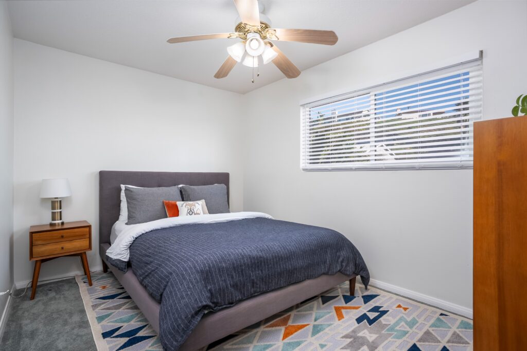 Bedroom at 2170 Montclair St in North Park San Diego with a large window, Venetian blinds, and a modern ceiling fan.