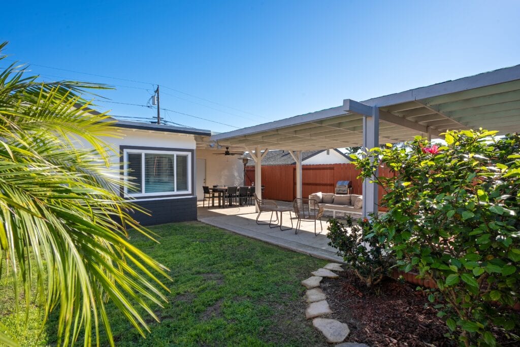 Wide-angle backyard shot of 2170 Montclair St, showing the transition from garden greenery to the large entertainer's patio with BBQ area.