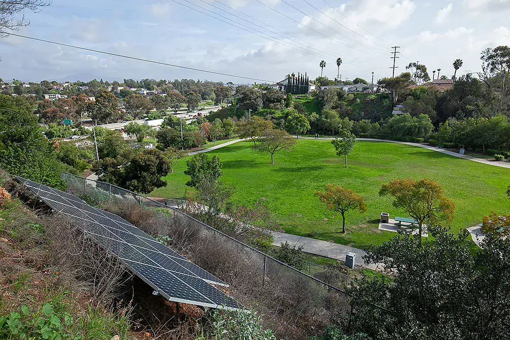 Elevated view of solar panels on a hillside overlooking a green park and walking paths in the North Park neighborhood of San Diego.
