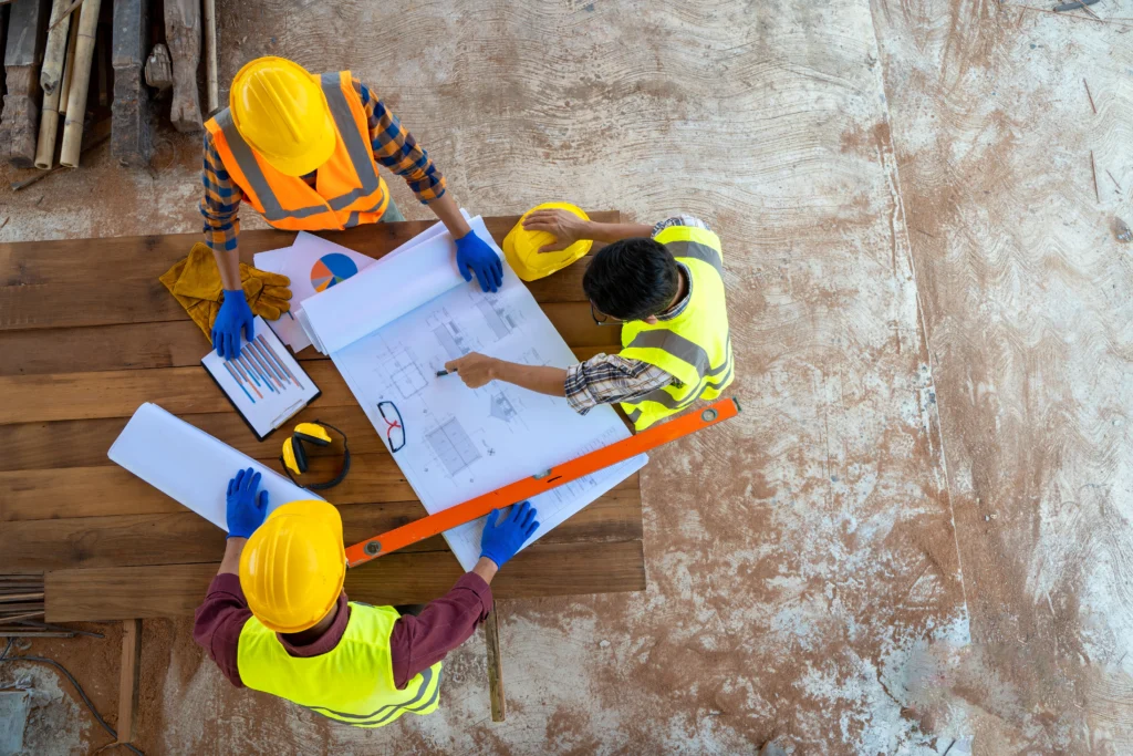Contractors discussing building plans and project data on site using blueprints and charts