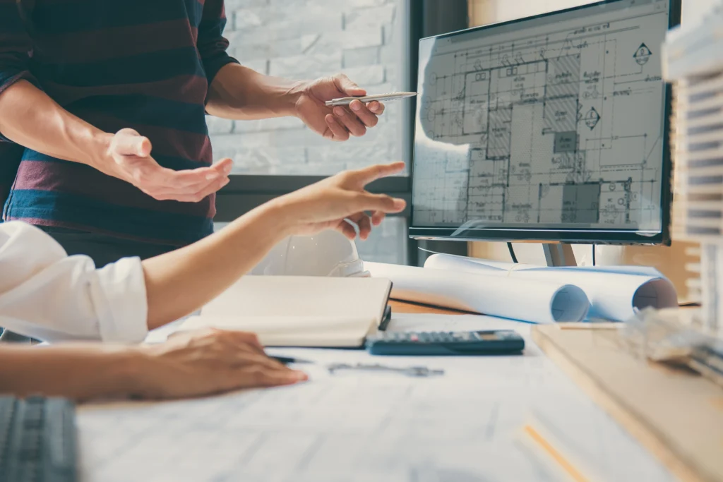 Team of architects reviewing floor plan designs on a computer monitor in a modern office