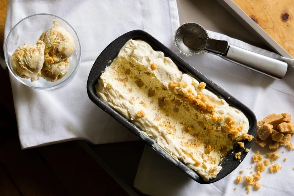 Tablet Ice Cream Recipe in a tub and a glass with scoop and Scottish tablet next to it.