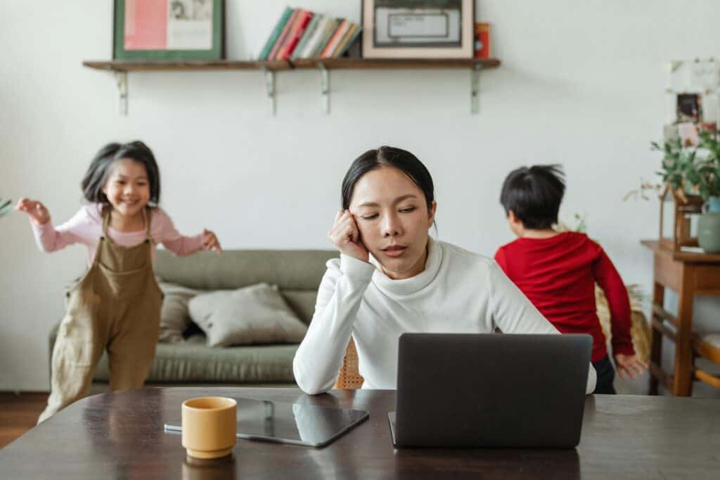 Overwhelmed woman and children playing in background, home therapy, mental health support, stress relief, family therapy, wellness at home.