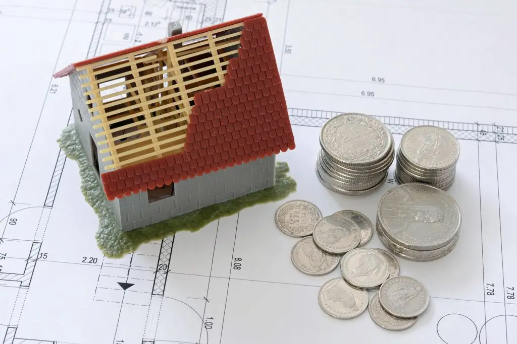 debt of coins and foreclosed property sitting on building blueprint