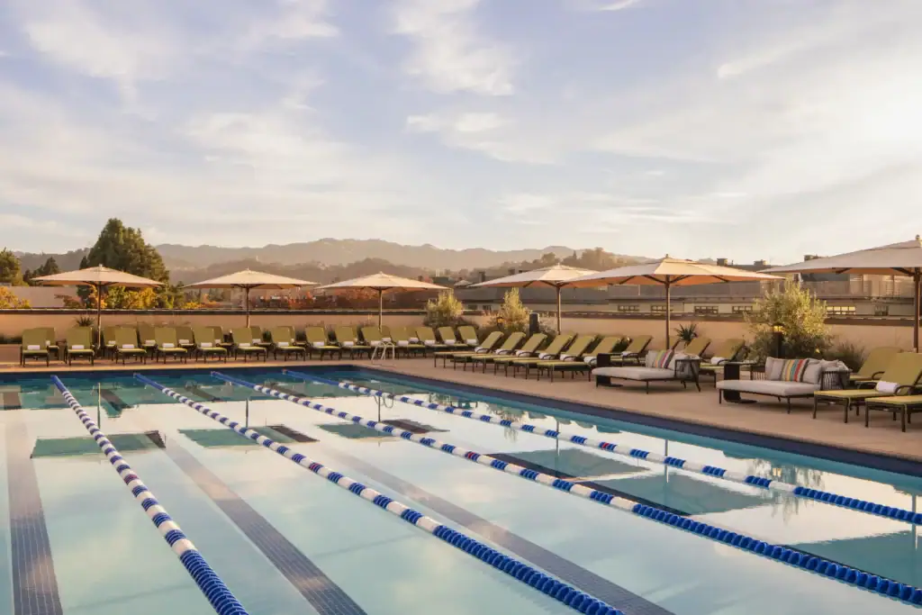 Outdoor lap swimming pool with dedicated swim lanes, lounge chairs, umbrellas, and scenic mountain views, offering a premium resort-style fitness and relaxation experience at a luxury Raleigh apartment.