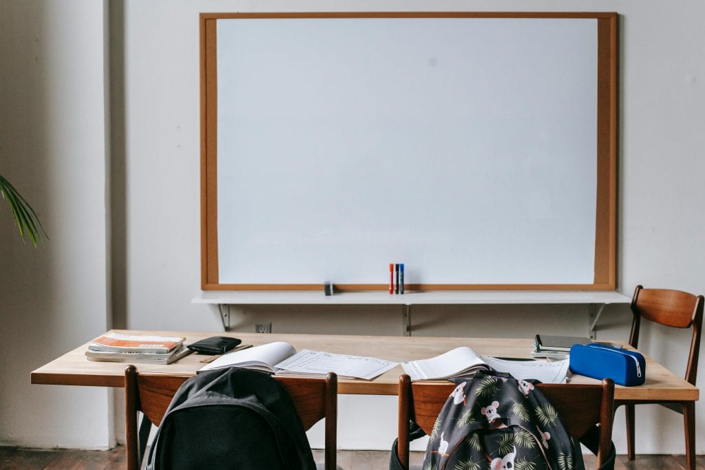 College classroom with a whiteboard and desk with school supplies