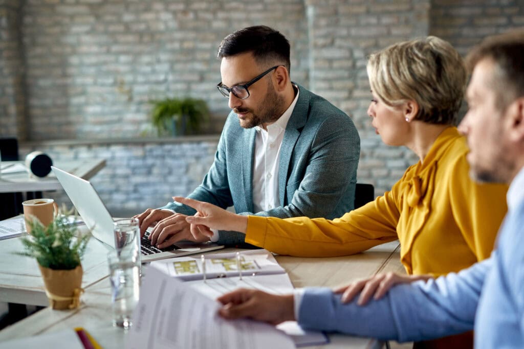 A Property Management employees working at a computer in their office while holding a meeting with investors