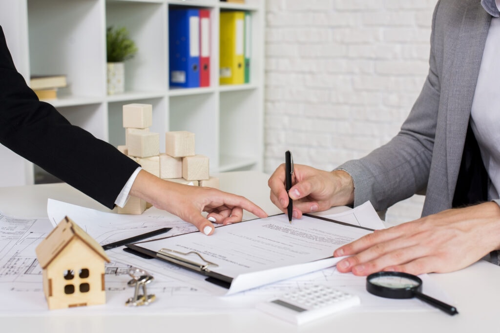 Two hands of different women signing a contract with a property management company