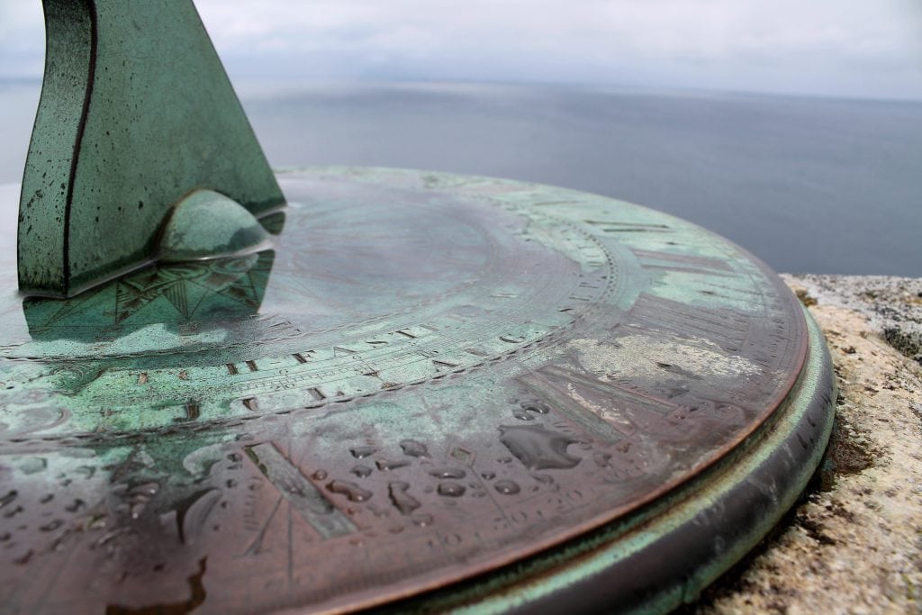 Der Anschnitt einer kupfernen Sonnenuhr mit Grünspan vor dem Meer