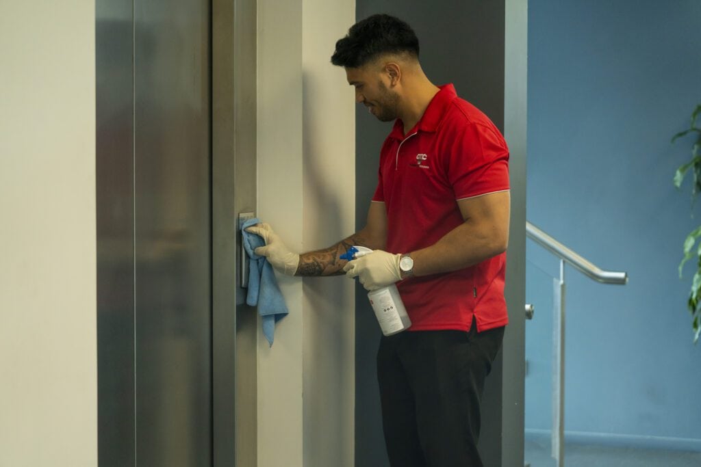 day and night office cleaner in uniform performing common area cleaning, including sanitising lift, switches, handles in Sydney and Parramatta buildings