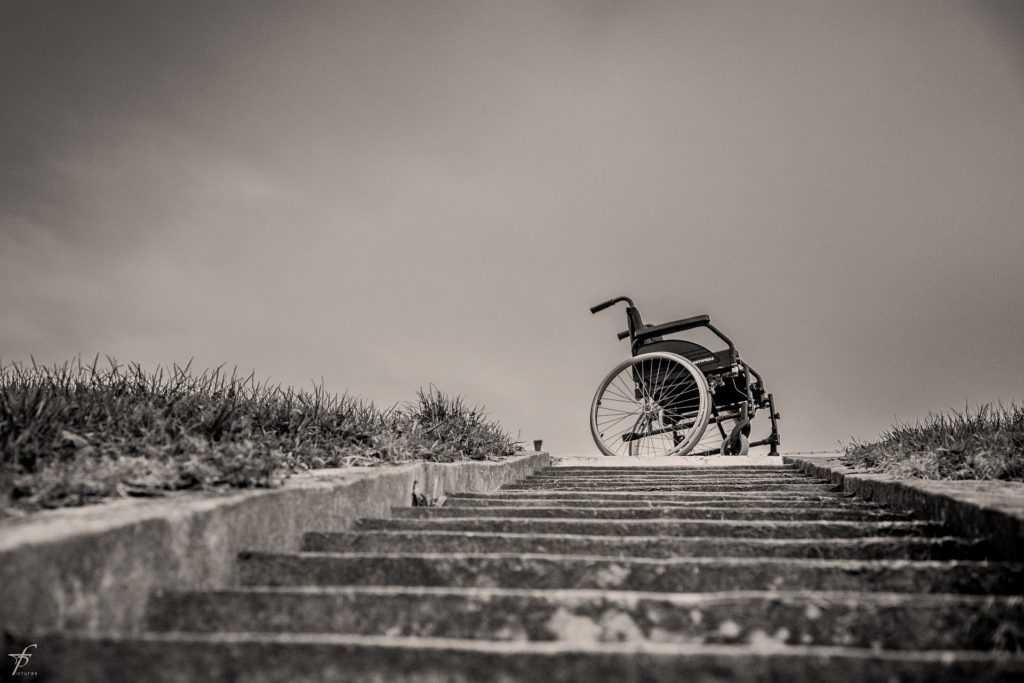 B/W photo of a wheelchair at the top of a flight of steps.