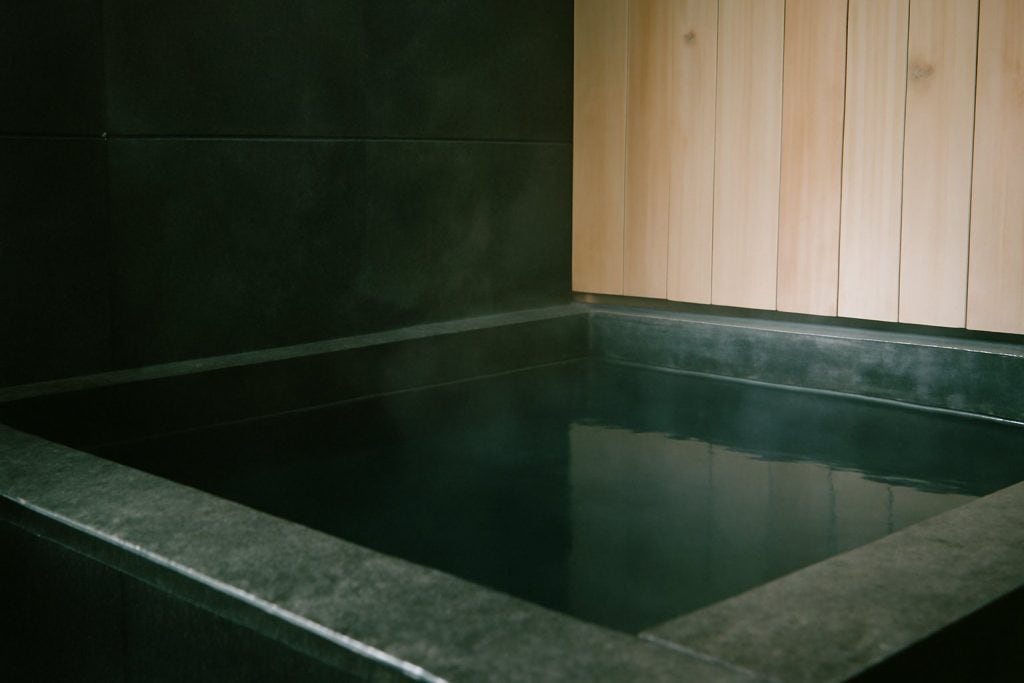 Bassin de bain froid en pierre sombre, eau froide et fine vapeur — H2O Saint-Étienne