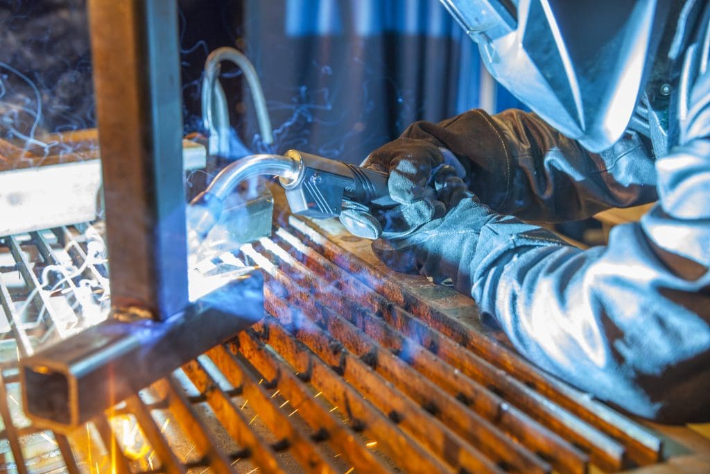 Welder welding with a Bernard semi-automatic MIG gun with T-series handle.