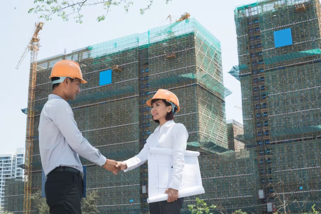 Arquitectos estrechando manos en obra de construcción, símbolo de alianza profesional, confianza y éxito en proyectos inmobiliarios.