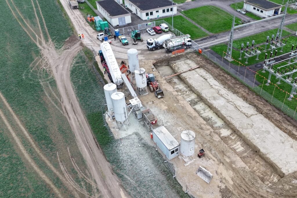 Luftaufnahme einer Baustelle am Umspannwerk mit vorbereiteter Gründung und Silostation für Flüssigboden, das Material wird vor Ort angemischt und in Baugruben eingebracht