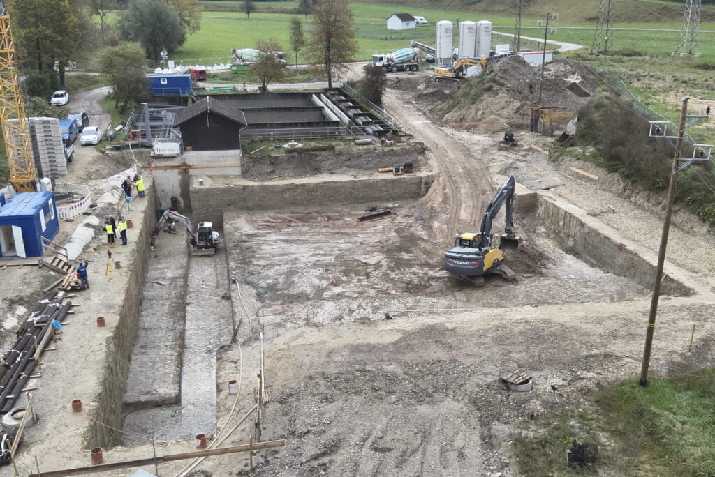 Großflächige Baugrube im Tiefbau mit mehreren Arbeitsebenen, Baggerarbeiten laufen, Silos und Technik für den Einsatz von Flüssigboden nach dem RSS-System sind eingerichtet