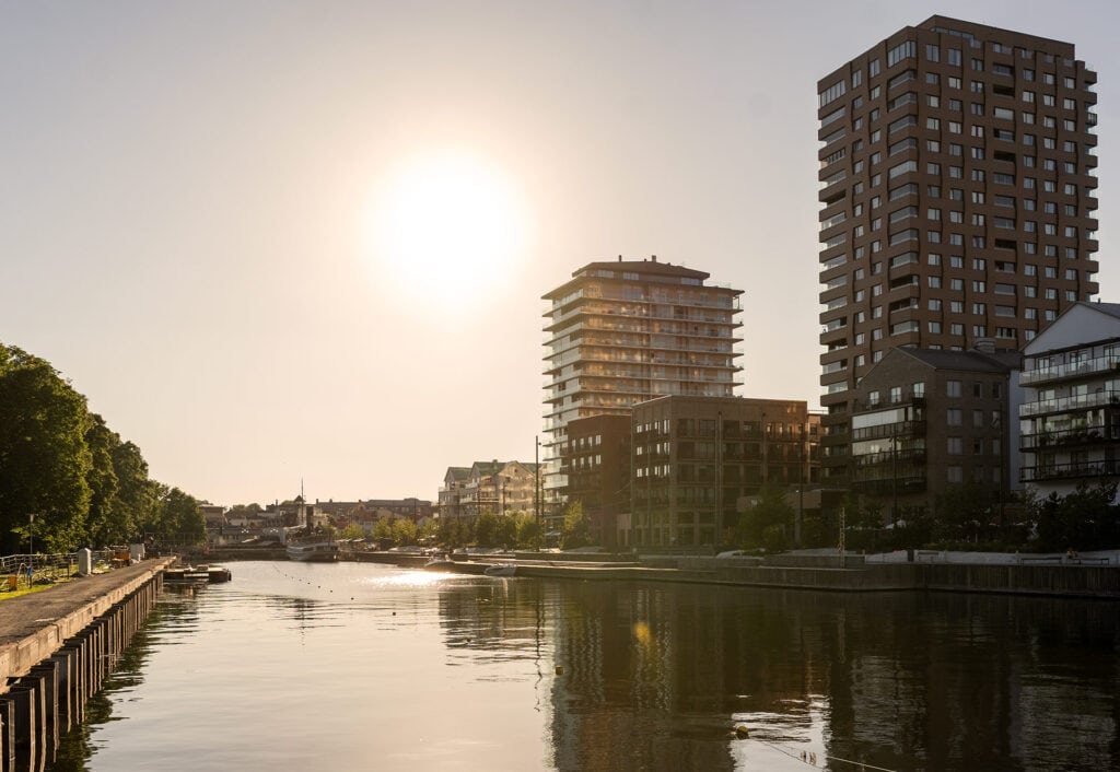Bild på fastigheter som har fjärrvärme. Solig vy över kaj, vattendrag och moderna höghus i stadsmiljö i Norrtälje.