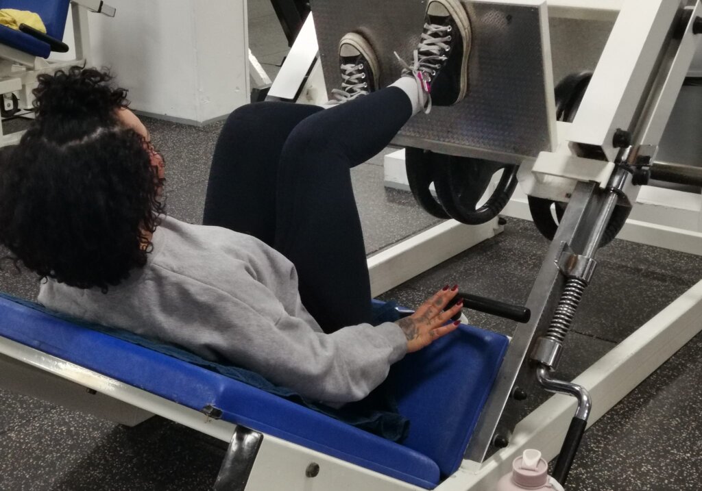 Dame voert een leg press uit op een fitnessapparaat, gefocust op kracht en controle tijdens haar training.
